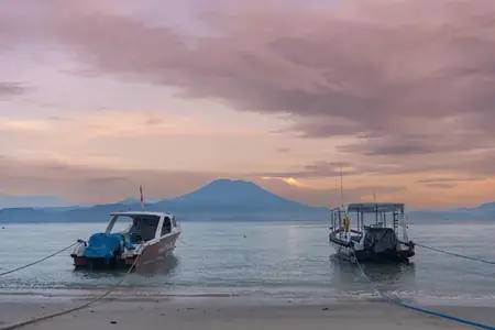Boats on the water at sunset with Mount Agung behind
