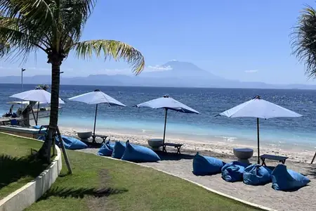 Beach sunbeds and parasols on Nusa Penida with Mount Agung on the horizon