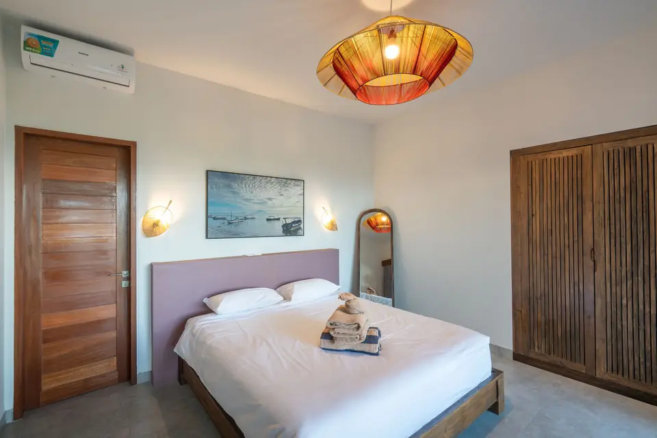 Casa Om bedroom with rattan pendant lamp and wooden wardrobe